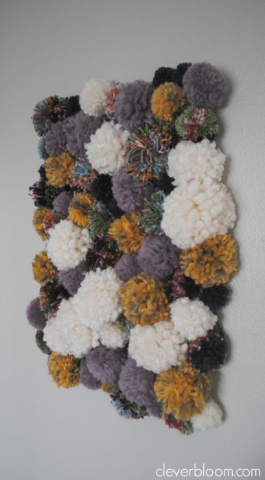 Visit cleverbloom.com for easy to follow instructions on how to make this DIY Pom Pom Wall Hanging. It's super groovy with a 70's vibe that will make a great conversation piece!
